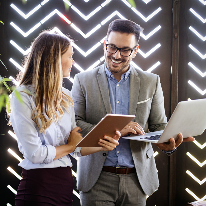 Colleagues discussing work beside a laptop